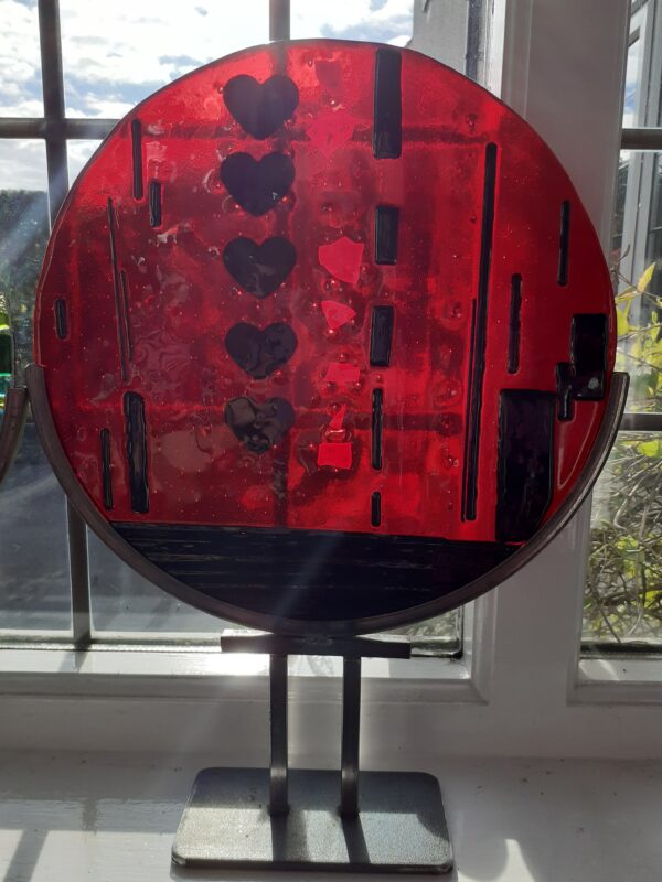 Fused glass disc in red and black (hearts) with metal stand